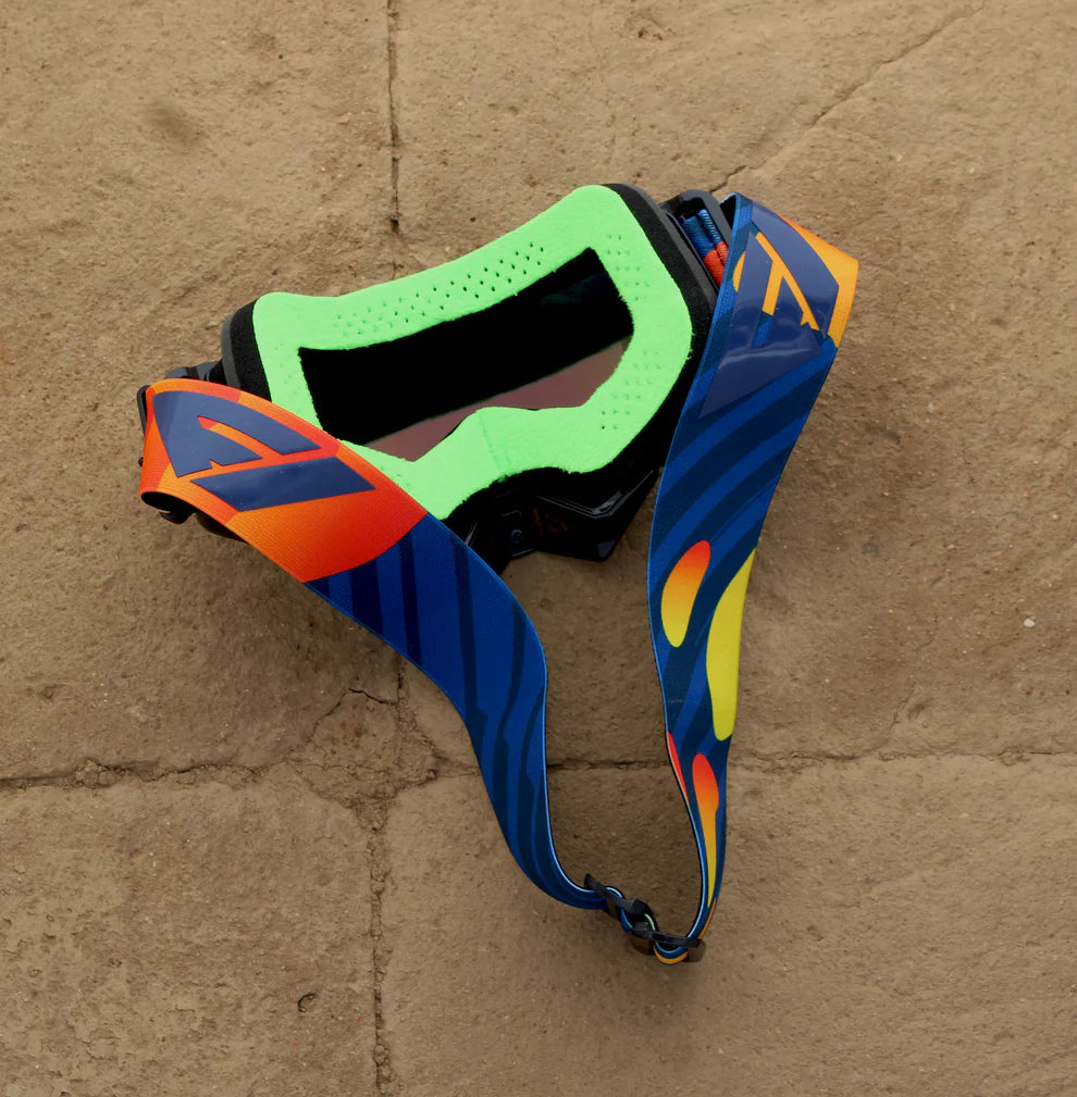 Colorful goggles with a blue strap on a textured brown surface