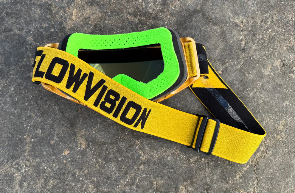 Goggles featuring green face foam with a gold strap labeled 'FLOWVISION' on a gray surface