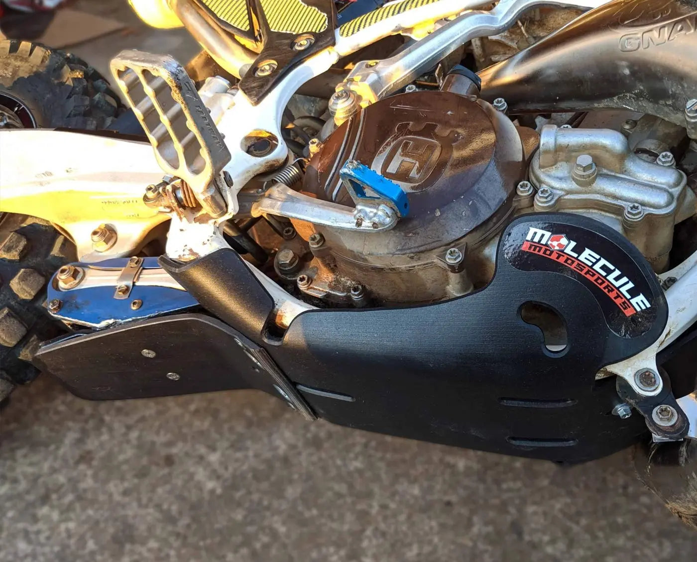 Close-up of a motorcycle skid plate and engine with 'Molecule' branding on a blurred background