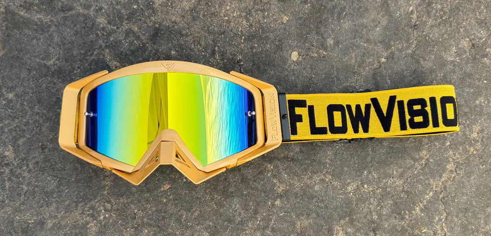 Goggles with a gold frame and reflective lenses on a textured surface, featuring 'FlowVision' branding.