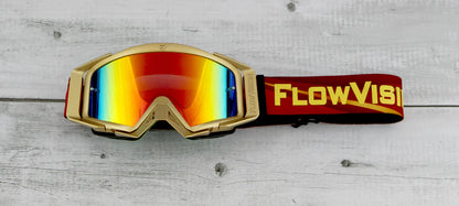 Gold-framed goggles with red mirrored lenses and a red 'FlowVision' strap on a wooden surface.