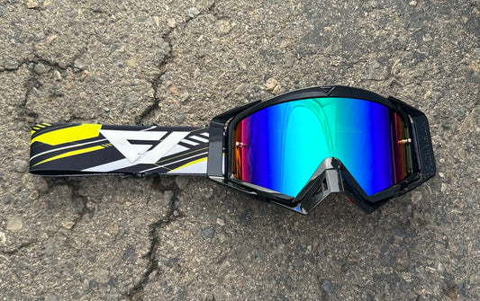 Reflective goggles with colorful lenses on a textured surface