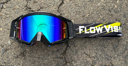 Goggles with reflective blue lens and 'Flow Vision' strap on a textured surface