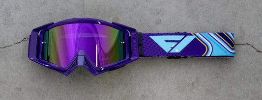 Purple goggles with a colorful strap on a concrete surface