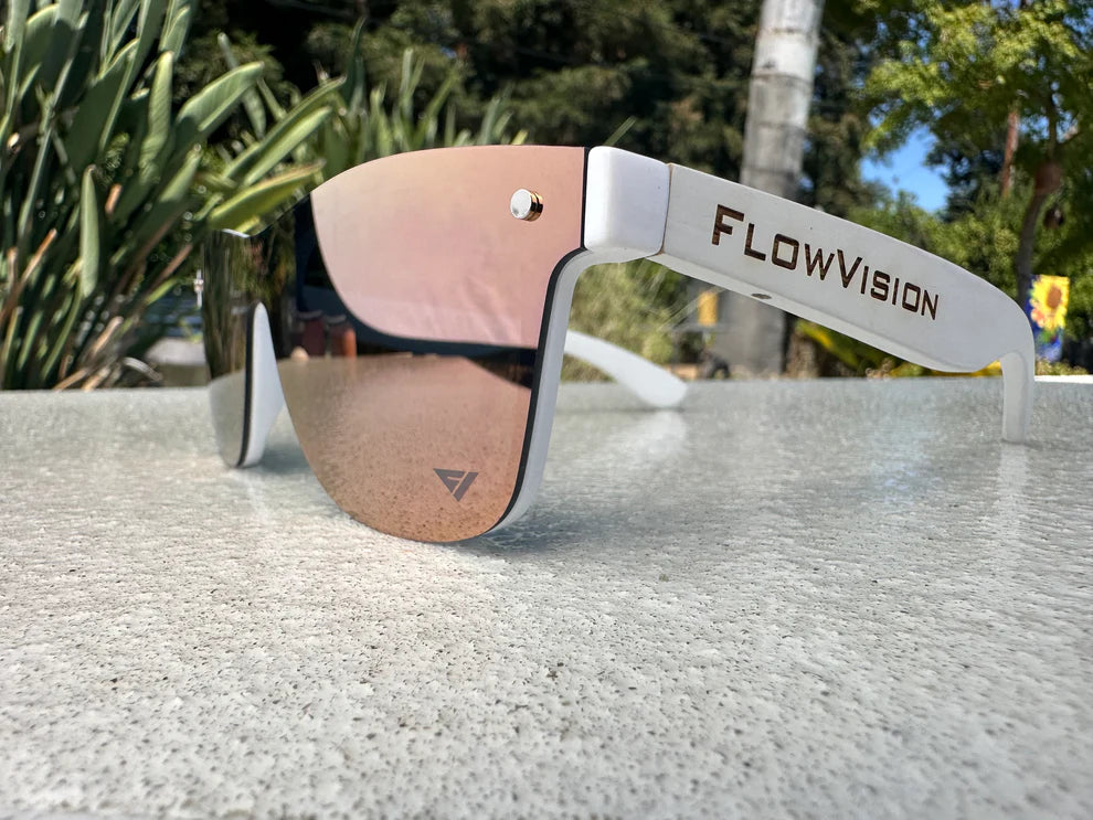 FlowVision sunglasses with pink lenses on a reflective surface outdoors