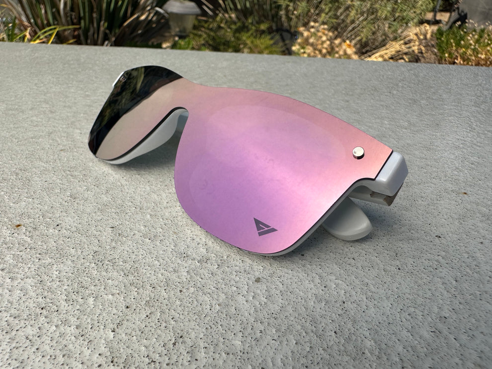 Sunglasses with pink reflective lenses on a concrete surface