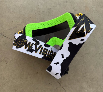 Goggles with green face foam and 'Flow Vision' branding on a concrete surface