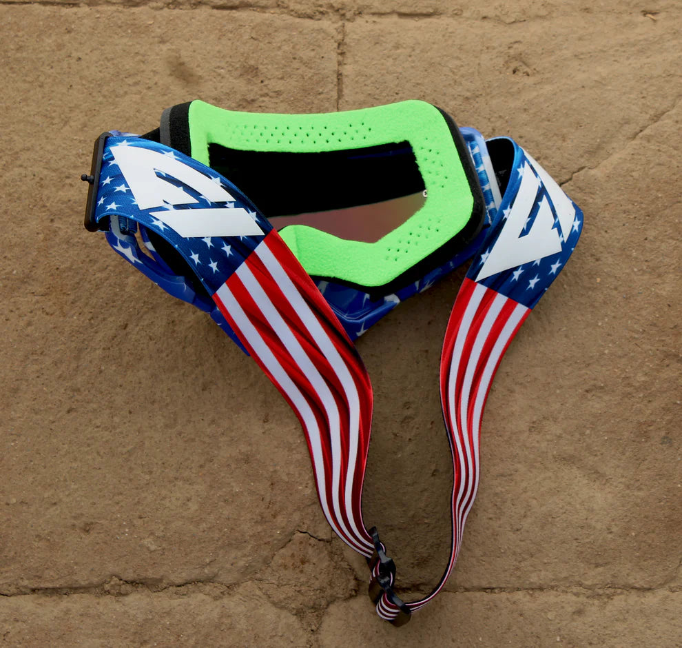Goggles with American flag strap on a stone surface