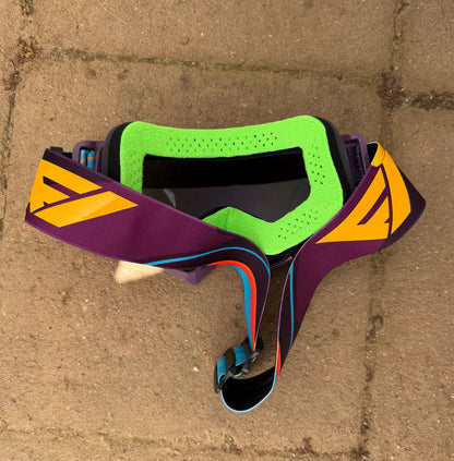 Flow Vision GTO purple goggles on a concrete surface