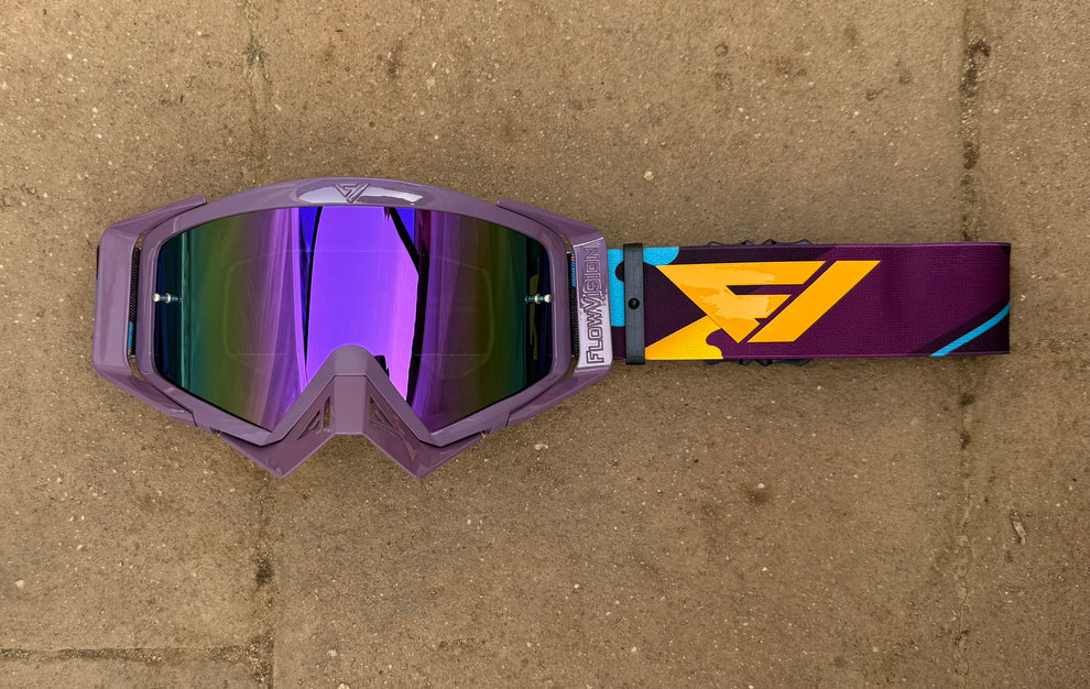 Purple goggles with a reflective lens on a brown surface
