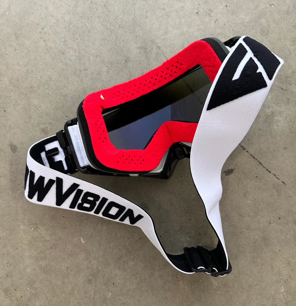 White and black goggles with a white strap on a concrete surface