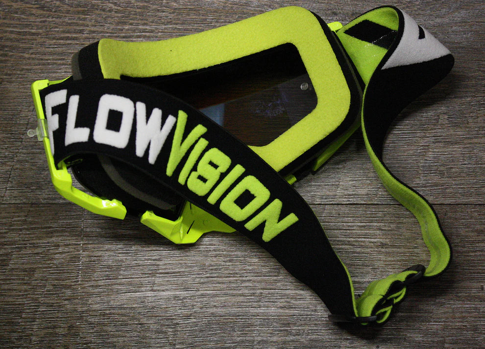 Neon green goggles with 'FlowVision' branding on a wooden surface