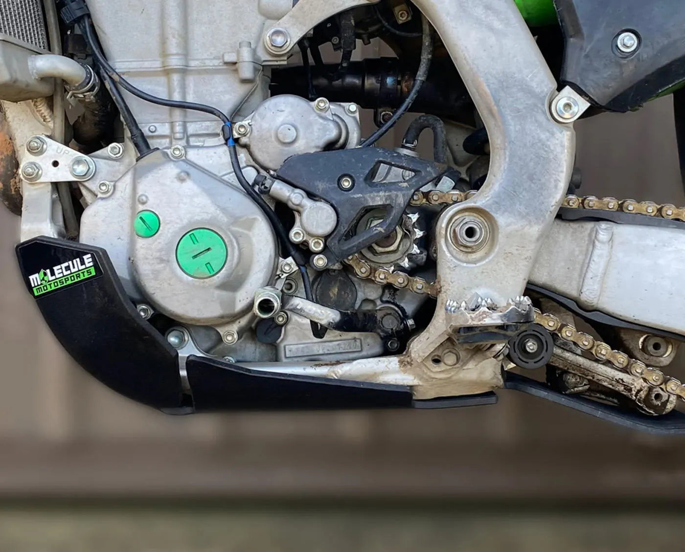 Close-up of a motorcycle chain and sprocket with a visible brand logo.