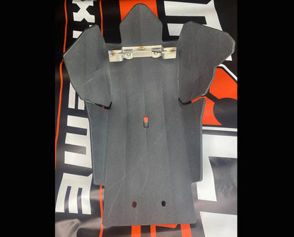 Black UHMS plastic dirt bike skid plate on a black and orange background with visible branding.