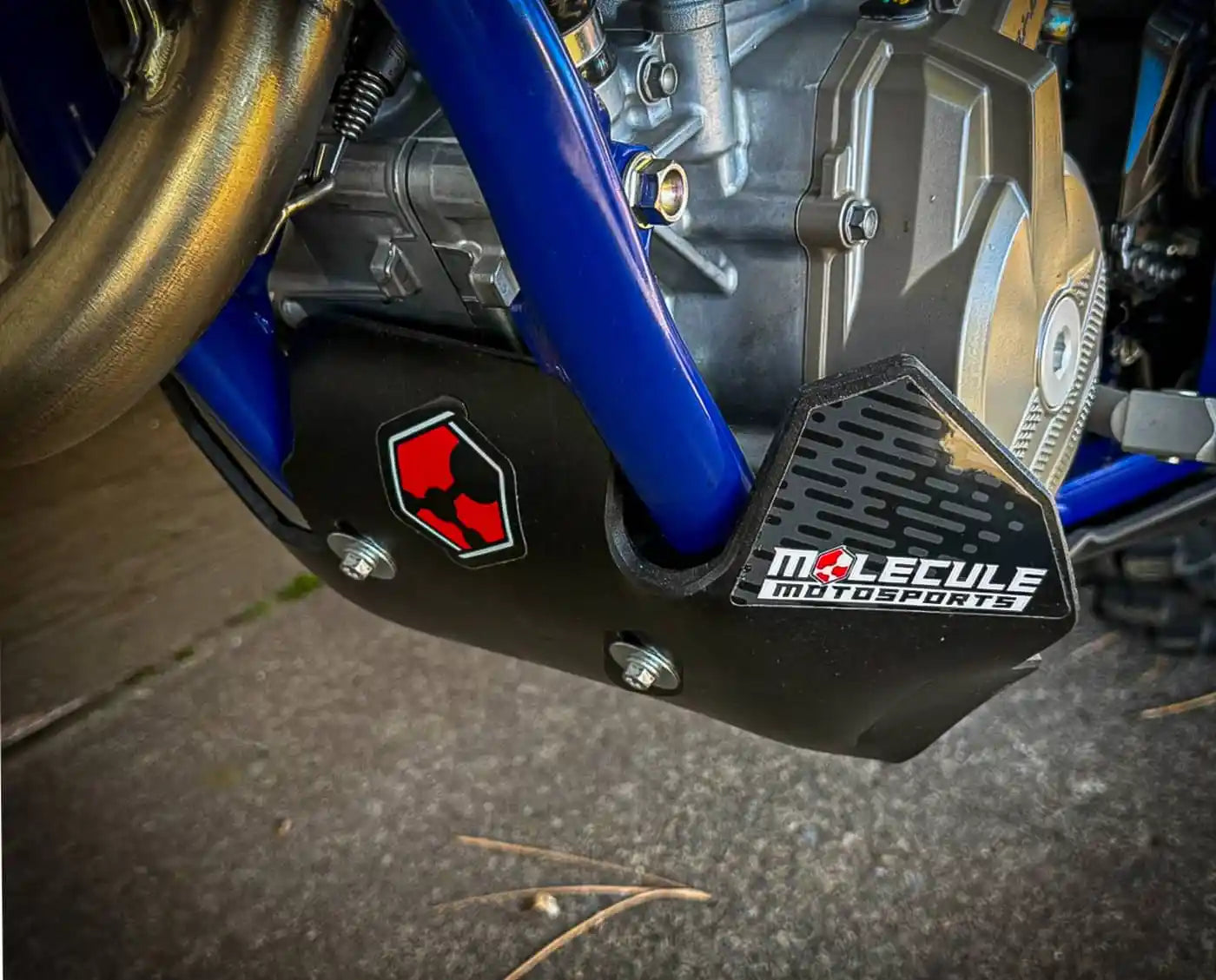 Close-up of a motorcycle engine cover with Molecule Motorsports skid plate and branding.