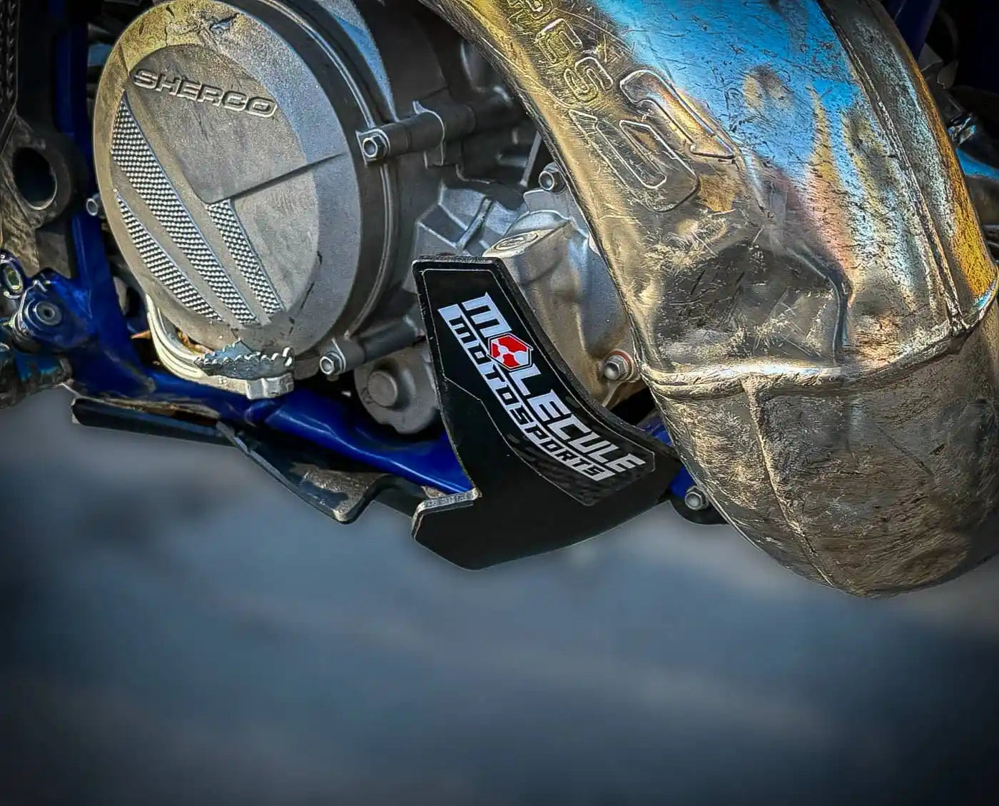 Close-up of a motorcycle engine with Molecule Motorsports branding and skid plate on a dark background