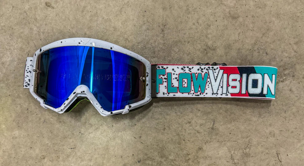Goggles with a colorful 'Flow Vision' strap on a beige background