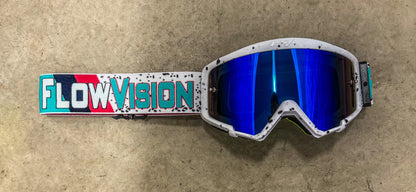 Motocross goggles with 'FlowVision' strap on a beige surface